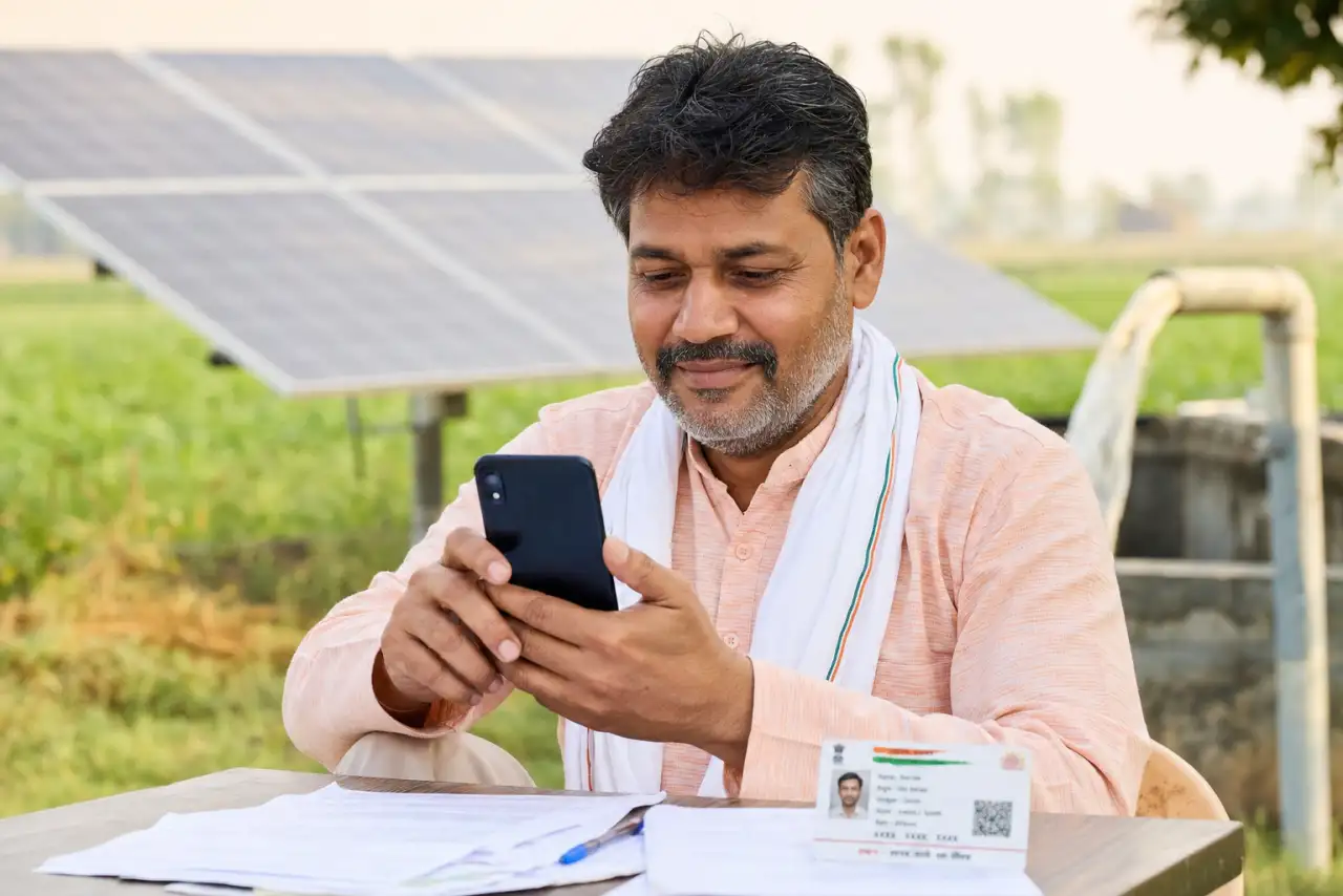 Maharashtra farmer applying online for the Kusum solar pump yojana on a smartphone with documents